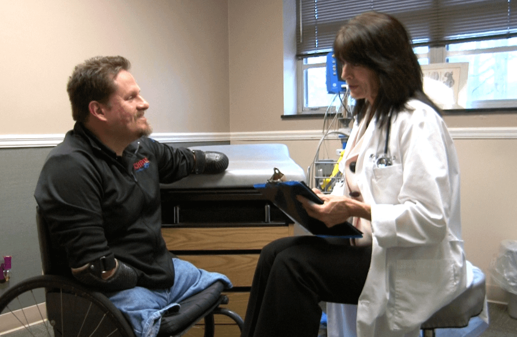 Man without feet and hands talking to a doctor