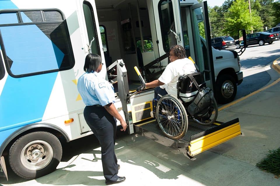 A women is using an accessibel bus lift with her wheelchair.